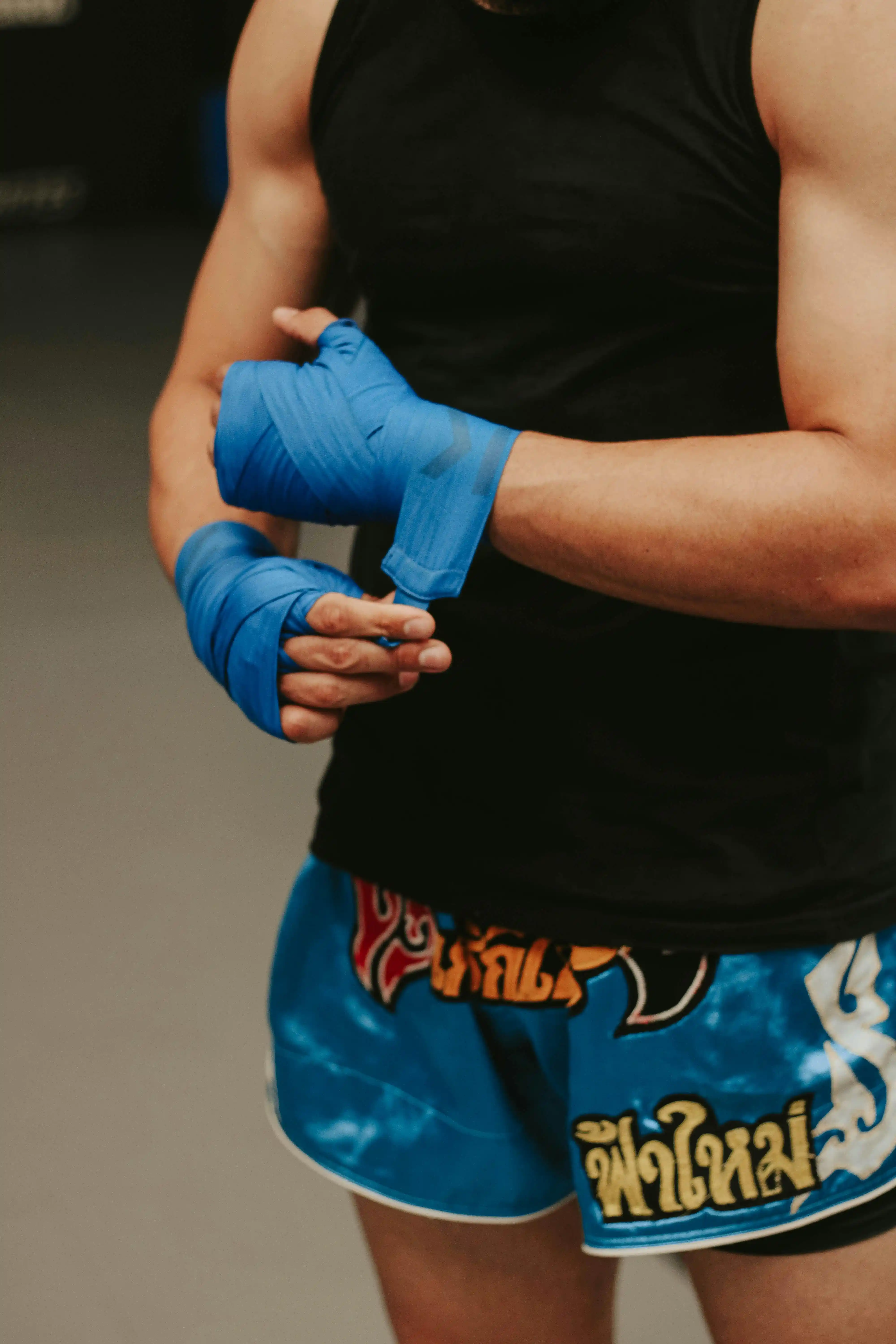 Fighter wrapping hands with blue wraps â preparing for Muay Thai training